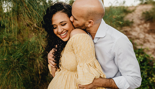 An expecting couple holding each other.